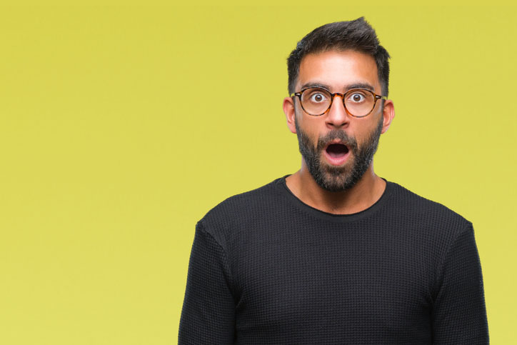 Adult hispanic man wearing glasses over isolated background afraid and shocked with surprise expression, fear and excited face.